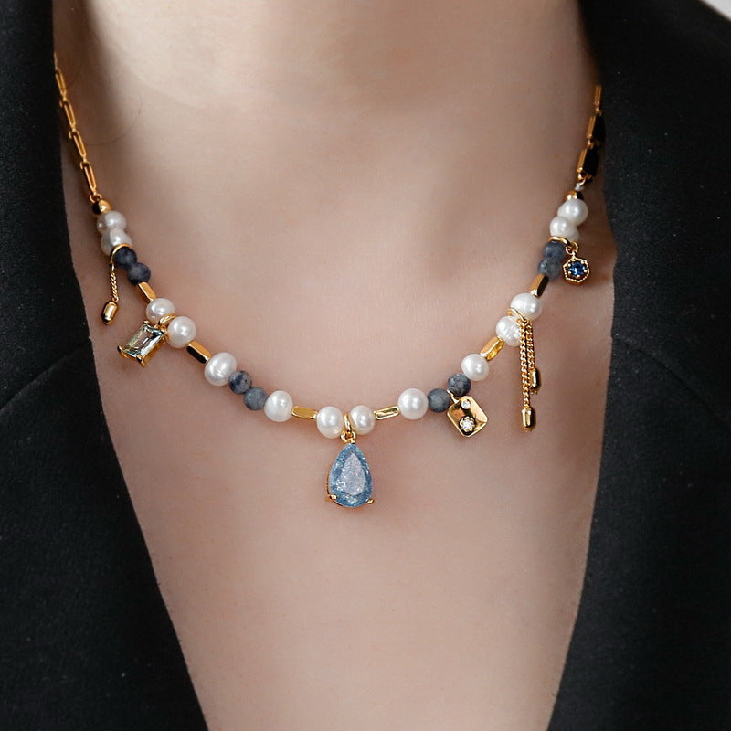 Necklace with pearls and blue teardrop pendant on a black background