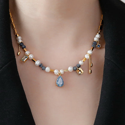 Necklace with pearls and blue teardrop pendant on a black background