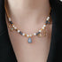 Necklace with pearls and blue teardrop pendant on a black background