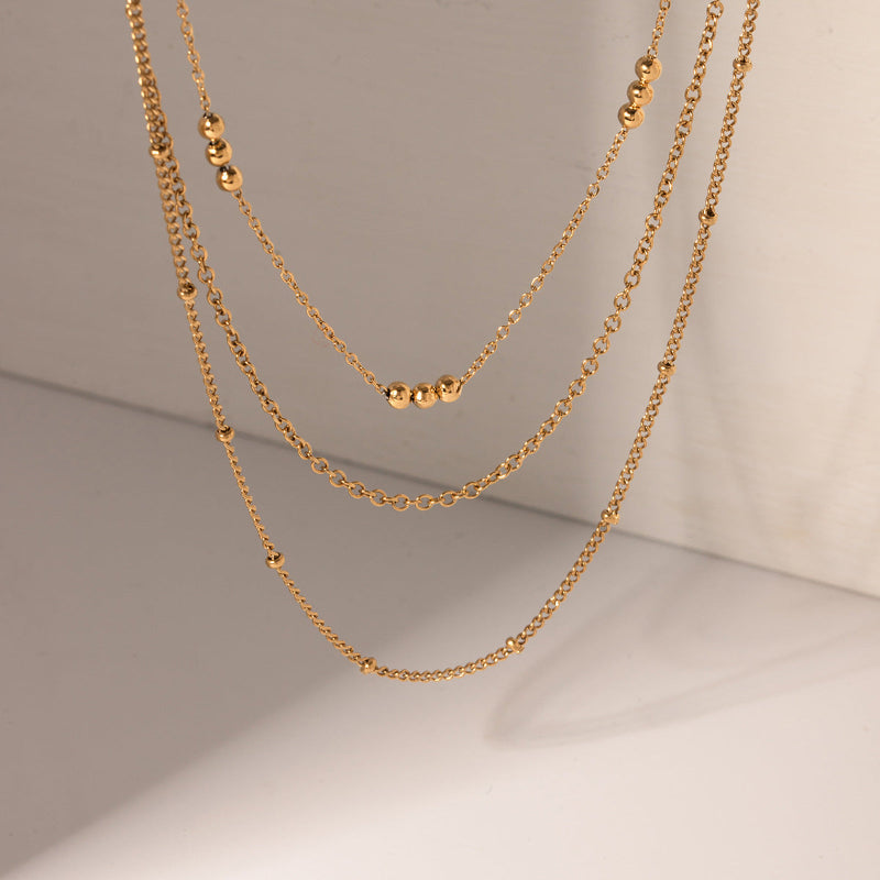 Two gold chains on a neutral background