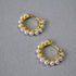 Pair of gold hoop earrings with pearl beads on a gray background