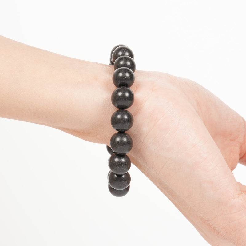 Black beaded bracelet on a wrist against a white background