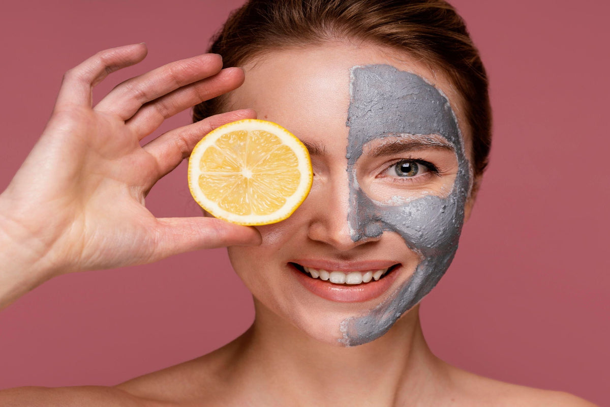 Woman with half of her face covered by a lemon and the other half by a gray mask on a pink background