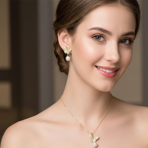 Woman wearing a gold necklace and pearl earrings with a blurred background