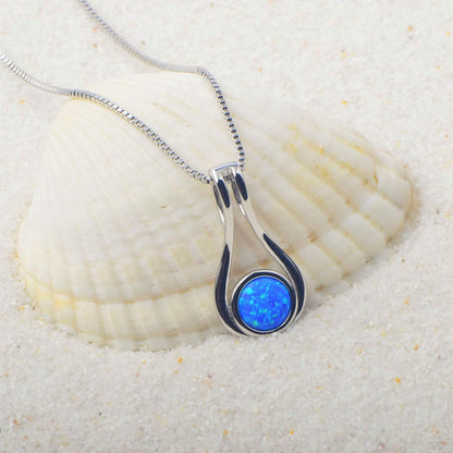 Silver pendant with a blue opal stone on a white shell background