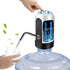 Hand pressing a button on a water dispenser with a glass being filled.