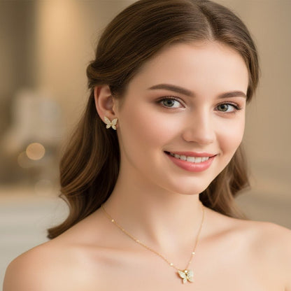 Woman wearing gold butterfly earrings and necklace against a blurred background